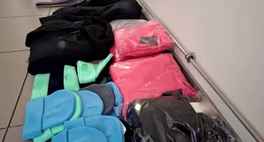 Odzież z podrobionymi znakami towarowymi w rękach policjantów 